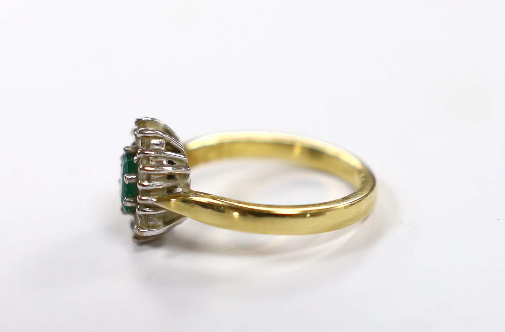 A modern 18ct gold, emerald and diamond set oval cluster ring, size L/M, gross weight 4.9 grams.